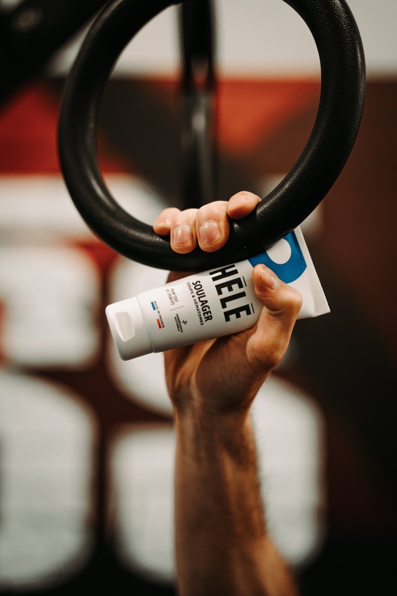 Main tenant un anneau de gym et un tube de gel pour les muscles et articulations